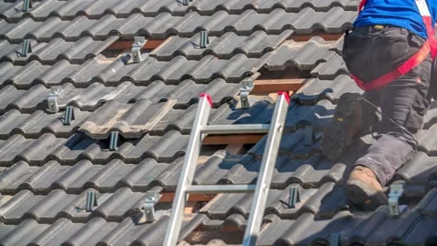 Worker Instal Mountings for Solar Panels on Roof, Sunny Day, Pan Right Stock Footage 150439904