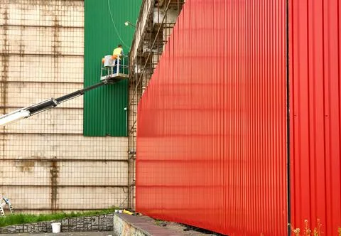 A worker installer fitter cladding panels from a crane on the wall of a house Stock Photos