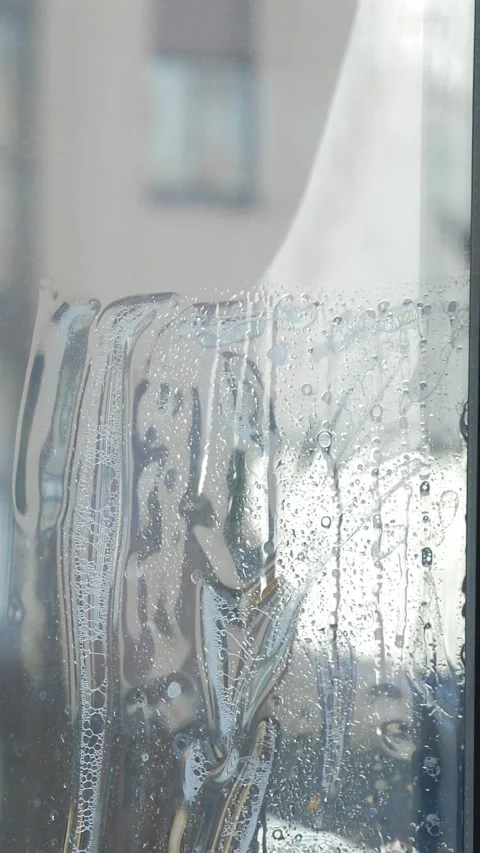 Worker installing and smoothing tint film on window at home. Man tinting windows Stock Footage 327127072
