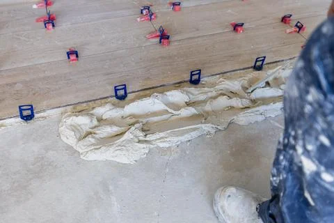 Worker installing ceramic tile flooring with leveling system Stock Photos