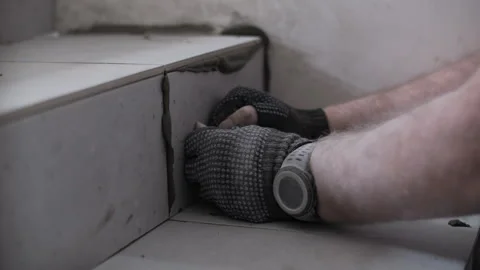 Worker installing ceramic tiles on staircase riser Stock Footage 314236429