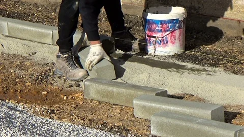 Worker installing concrete curb stone and using string with metal stakes to l Vídeo Stock 87045579