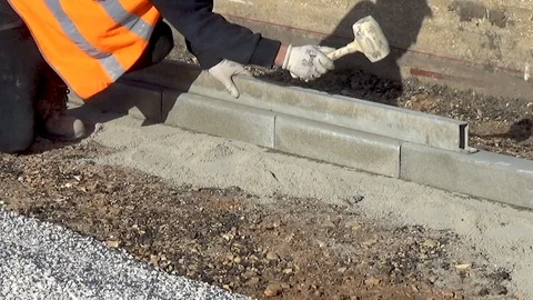 Worker installing concrete curb stone and using string with metal stakes to l 스톡 동영상 98604501