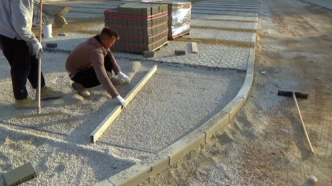 Worker installing concrete curb stone and using string with metal stakes to l Vídeo Stock 122986161