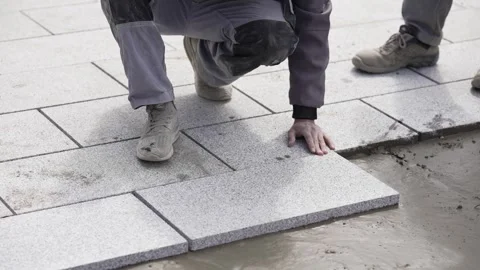 Worker installing concrete pavement tiles on a construction site, slow motion Stock Footage 304354460