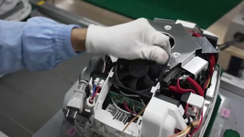 Worker installing cooling fan and connecting PCB board inside rice cooker body Stock Footage 334965169