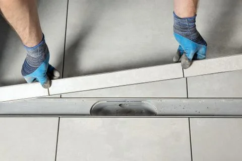 A worker is installing a drain lid. Stock Photos