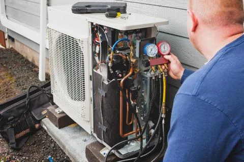 Worker installing ductless heat pump outdoors Stock Photos