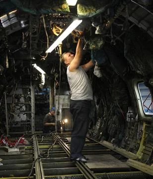 Worker installing electric wiring inside of a body plane. The State Aircraft Stock Photos