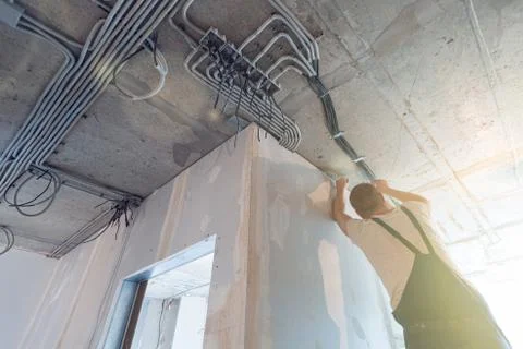 Worker is installing the electrical wires on the ceiling that is the part of Stock Photos