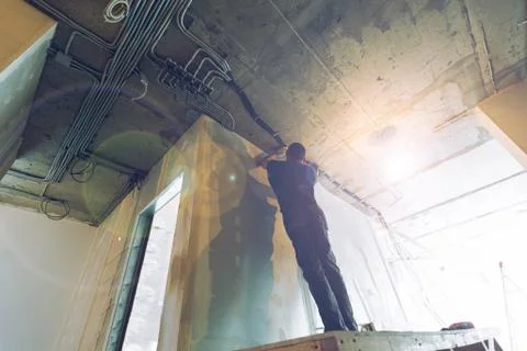 Worker is installing the electrical wires on the ceiling that is the part of Stock Photos