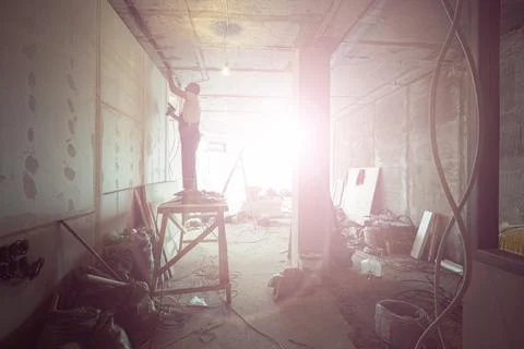Worker is installing the electrical wires on the ceiling that is the part of Stock Photos