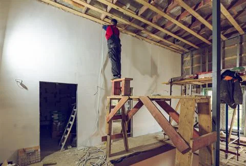 Worker is installing the electrical wires on the wall that is the part of Stock Photos