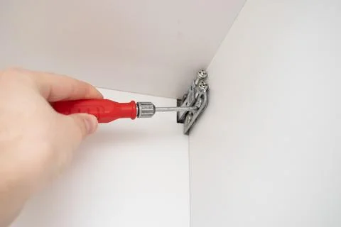 Worker installing a Fasteners for kitchen drawers to the wall. Stock Photos