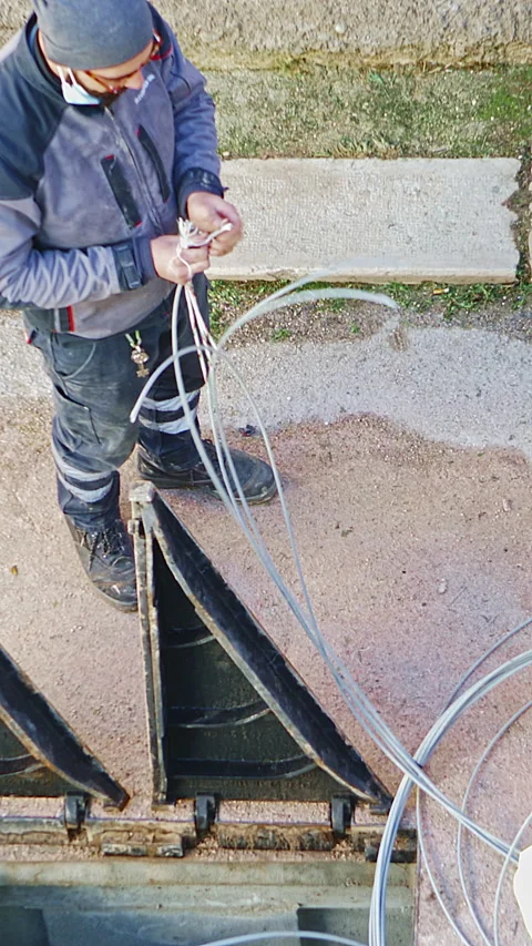 Worker installing fiber optic cables near an open utility box, wearing protec 動画素材 297088266