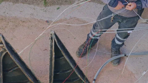 Worker installing fiber optic cables near an open utility box, wearing protec Stock-Footage 297088600