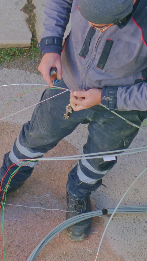 Worker installing fiber optic cables near an open utility box, wearing protec Stock-Footage 297088613