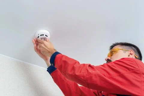 Worker installing fire alarm or smoke detector on the ceiling Stock Photos