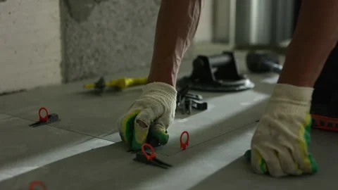 Worker installing floor tile leveling clips during interior construction Stock Footage 344473387
