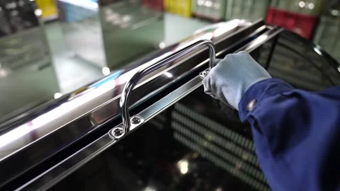 Worker installing handle bracket rail onto stainless steel bin lid in factory Stock Footage 345047716
