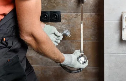 A worker is installing a heating element in the towel warmer. Stock Photos