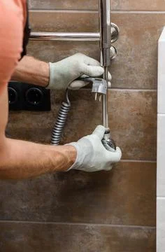 A worker is installing a heating element in the towel warmer. Stock Photos