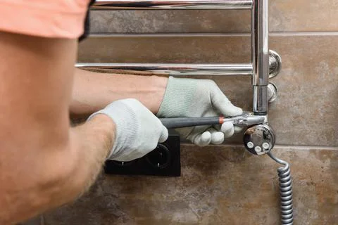 A worker is installing a heating element in the towel warmer. Stock Photos