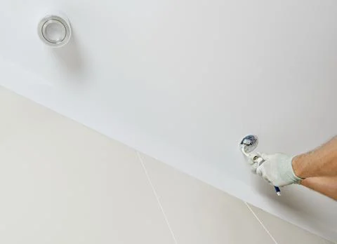A worker is installing an LED spotlight on the ceiling. Stock Photos
