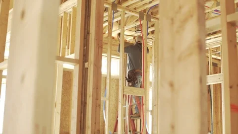 Worker installing light fixture in frame of house 库存影片 78714121