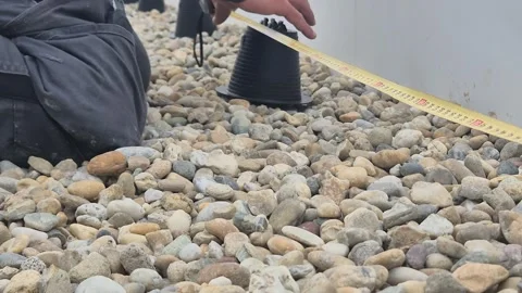 Worker Installing Lightning Protection Conductor Holder on Flat Gravel Roof Stockbeeldmateriaal 333984351