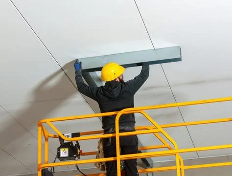 Worker installing metal profile for large plasterboard ceiling Stock Photos