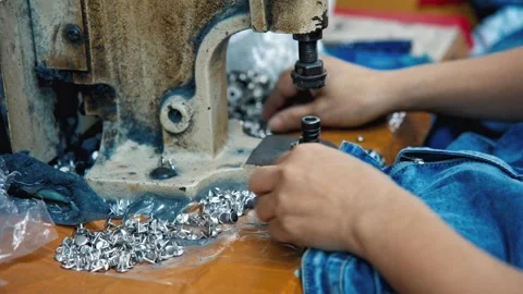 Worker Installing Metal Rivet Button on Blue Denim Jeans using Press Machine Stock Footage 335609877