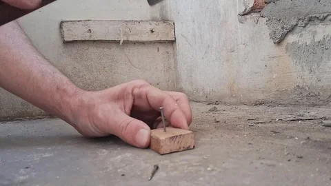 Worker installing a nail into concrete surface. Construction worker securing Stock Footage 340922450