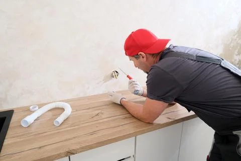 Worker installing new electrical socket on wall above countertop Stock Photos