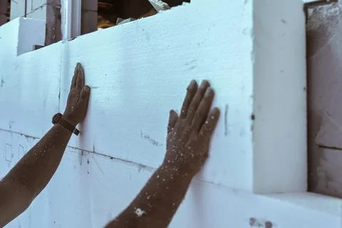 Worker installing polystyrene heat insulation on bare house walls, detail to Stock Photos