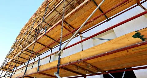 Worker installing scaffolding on building, showcasing the teamwork Stock Photos