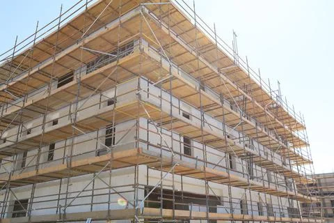 Worker installing scaffolding on building, showcasing the teamwork and safe.. Stock Photos