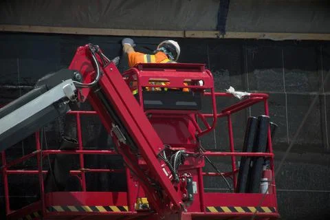 Worker installing a self-adhering waterproofing membrane on below-grade concr Stock Photos