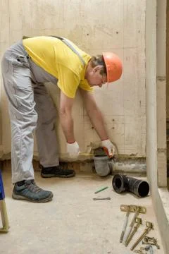 The worker is installing a sewage drain pipe. Stock Photos