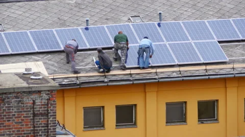 Worker installing solar panel roof top apartment Stock Footage