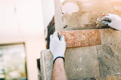 Worker installing stone tiles in construction site. masonry details Stock Photos