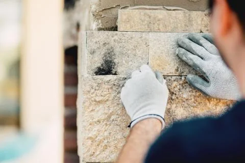Worker installing stone wall surface with cement for house renovating. Stock Photos