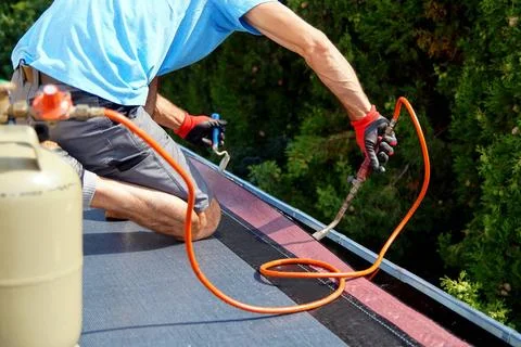 Worker installing tar foil on the rooftop of building. Flat roof installat... Fotos de archivo