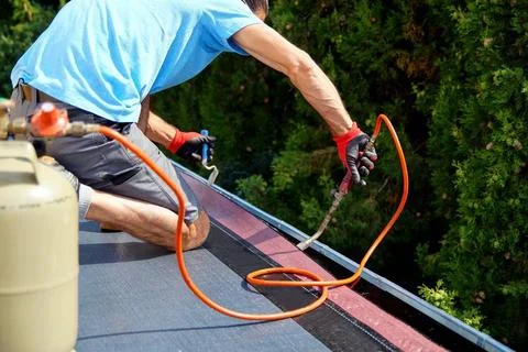 Worker installing tar foil on the rooftop of building. Flat roof installat... Fotos de archivo