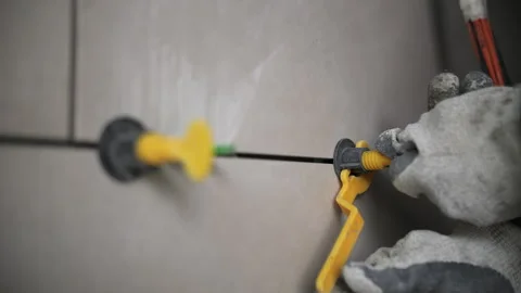 Worker installing tile leveling system on wall Stock Footage 314059154