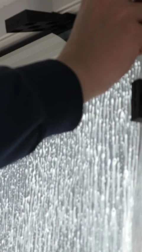 Worker installing tint film on window at home. Man tinting windows. Vertical Stock Footage 327133606