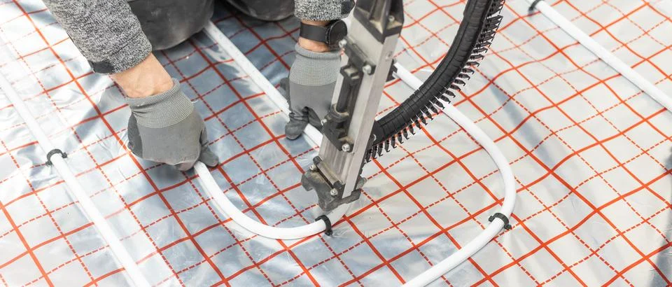 Worker installing underfloor heating system, water heating on the new Stock Photos