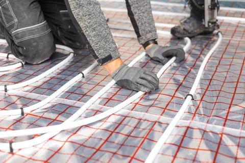 Worker installing underfloor heating system, water heating on the new Stock Photos