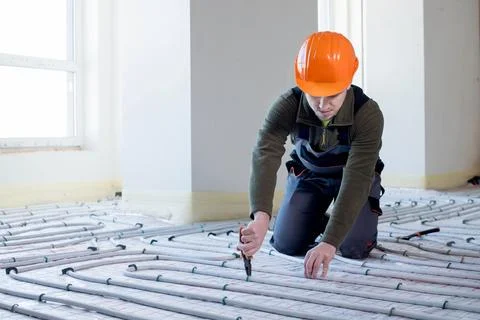 Worker is installing underfloor heating system. Warm floor heating system Foto stock
