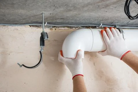 A worker is installing a ventilation system. Stock Photos